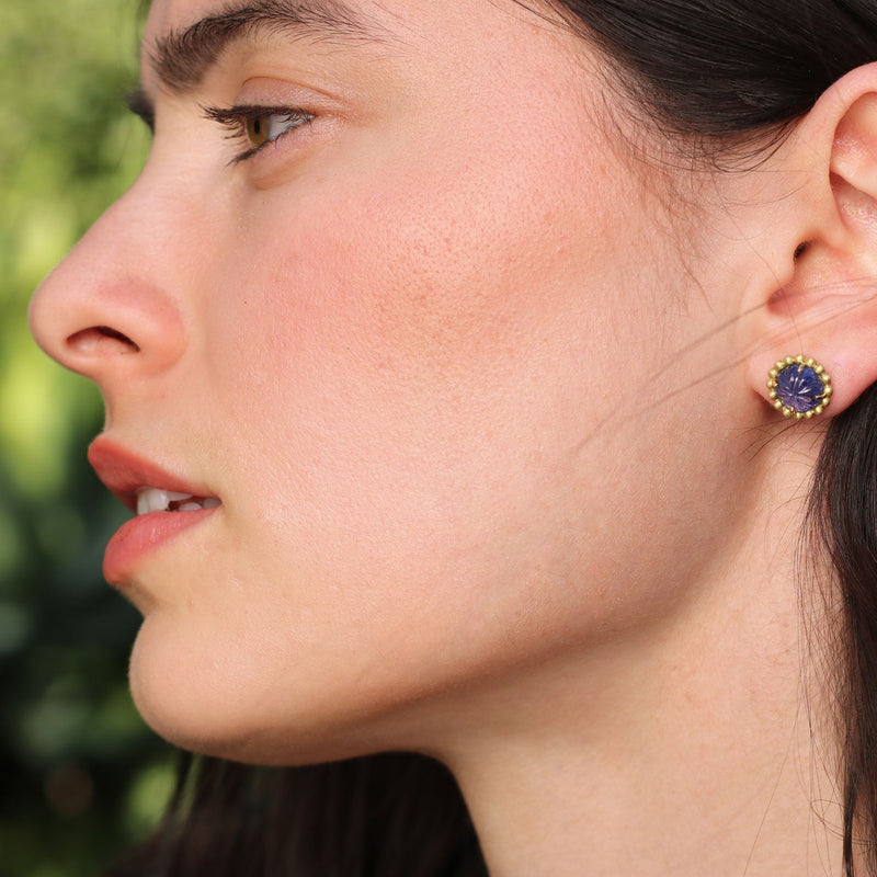 Model wearing Hand carved Tanzanite flower blossom earrings with 18k gold beaded surround. Fine jewelry hand made in London from Los Angeles designer Brooke Gregson. 