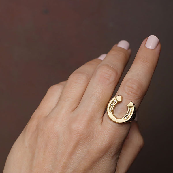 Hand showing 18k gold hand engraved horseshoe ring with diamonds by Los Angeles fine  jewelry designer Brooke Gregson.